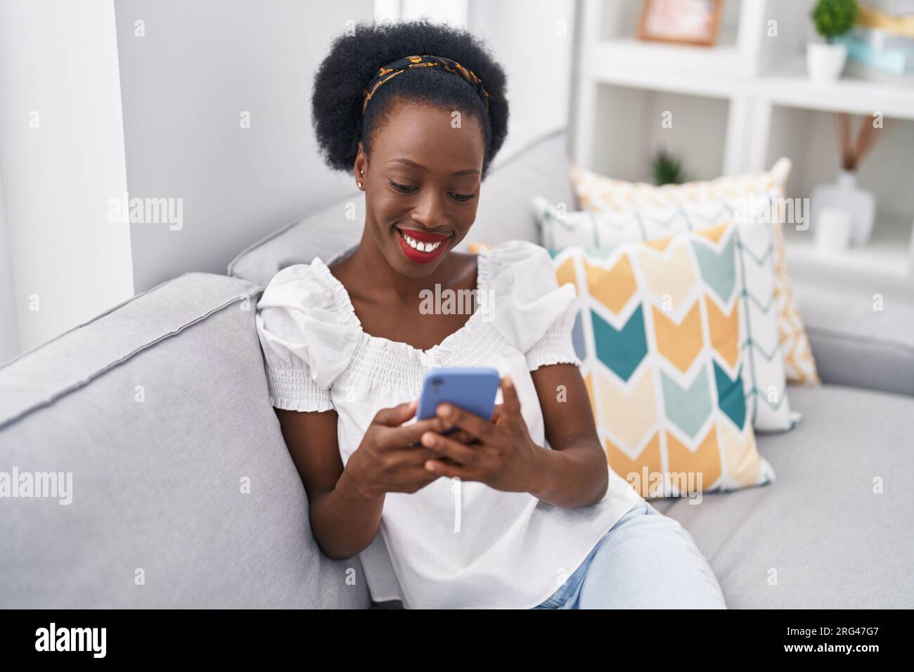 African american woman using smartphone sitting on sofa at home Stock ...