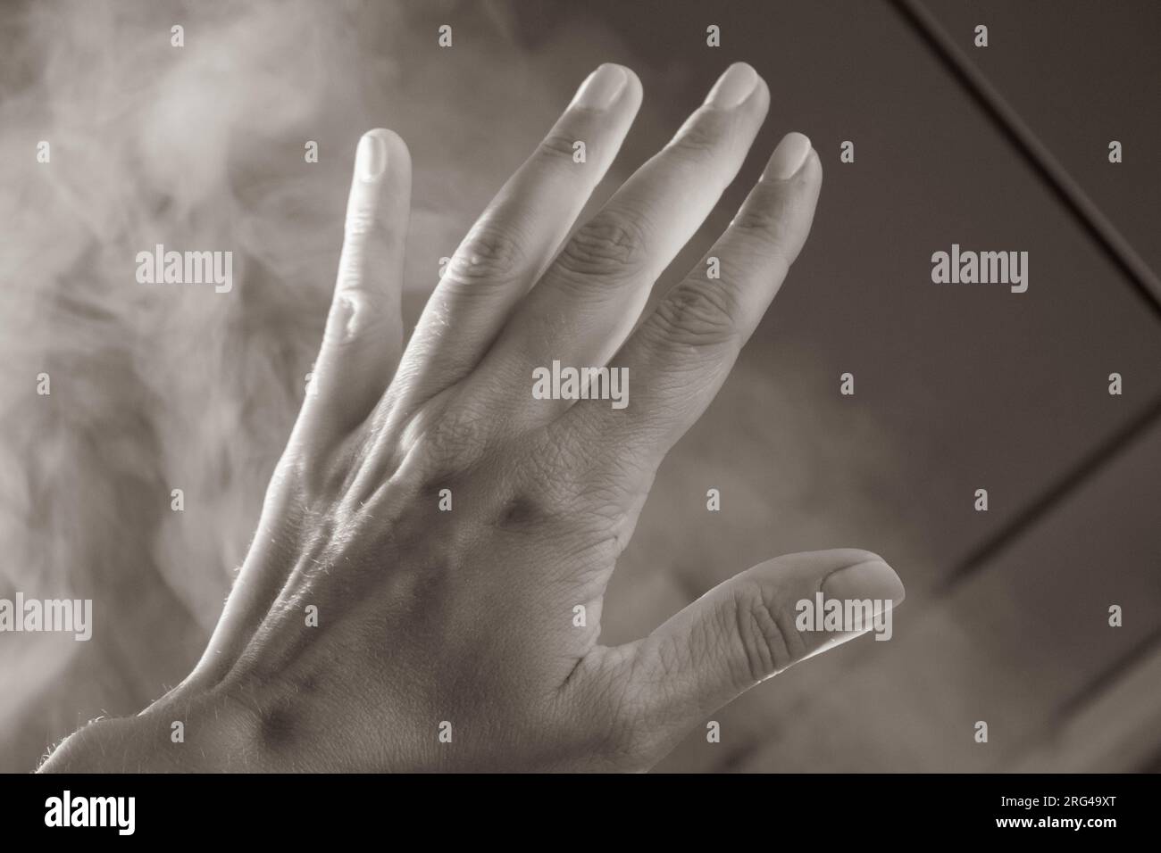Open palm with five fingers in fume. Human arm in natural light with shadows. Help gesture. Opacity concept. Woman hand in haze. Hand in the sky. Stock Photo