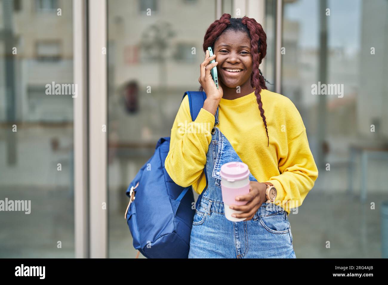 African american woman student talking on smartphone drinking coffee at ...