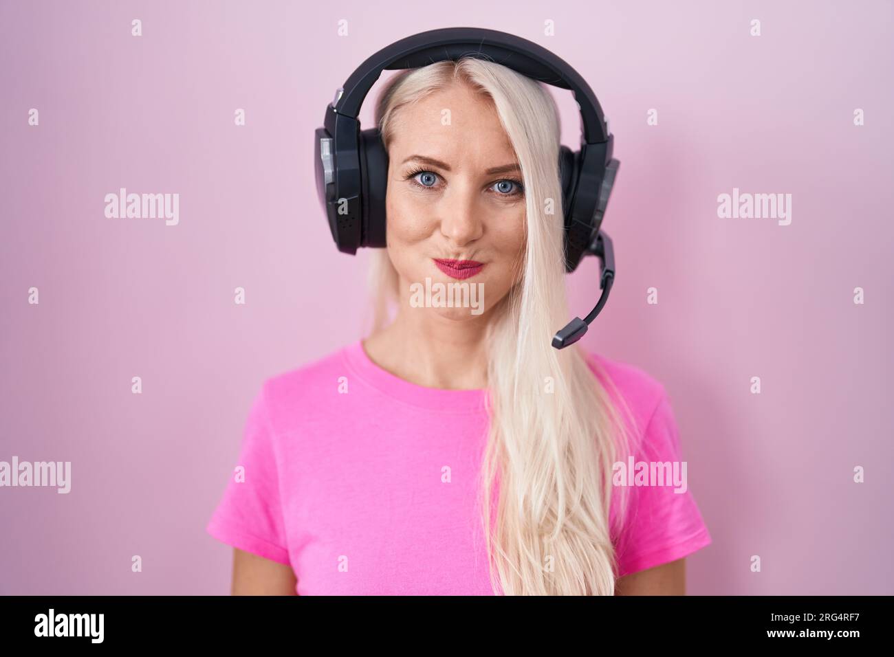 Caucasian woman listening to music using headphones puffing cheeks with  funny face. mouth inflated with air, crazy expression Stock Photo - Alamy