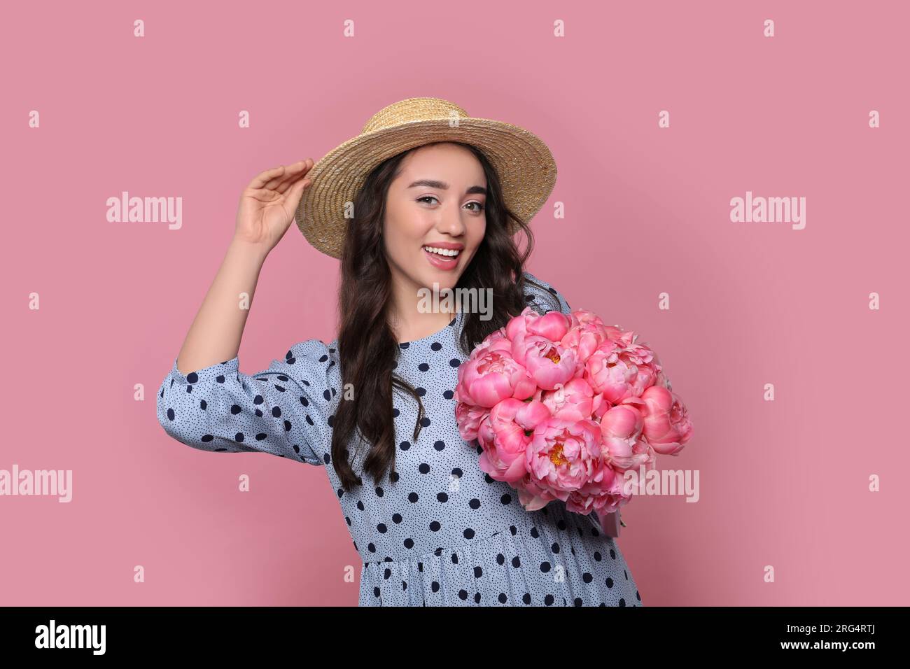 Beautiful young woman in straw hat with bouquet of peonies on pink ...