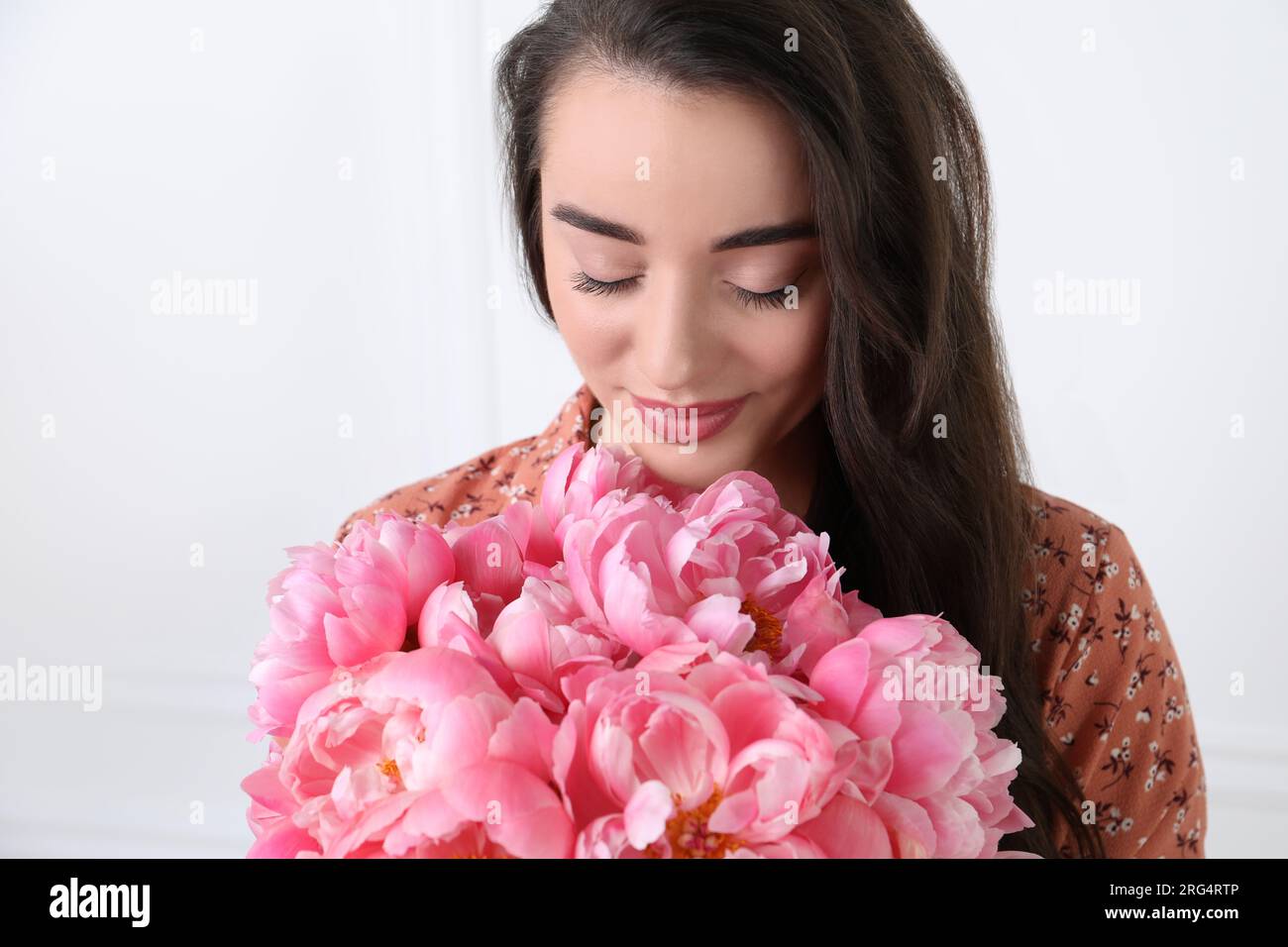 Beautiful young woman with bouquet of pink peonies on white background ...