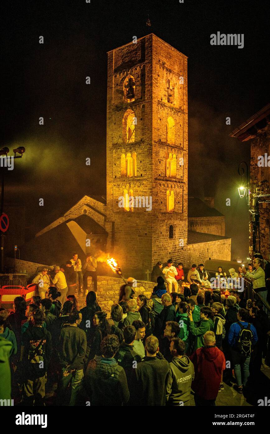 Neighbors passing in front of the church of the Nativitat de Durro on the Falles descent of 2023 (Vall de Boí, Lleida, Catalonia, Spain, Pyrenees) Stock Photo