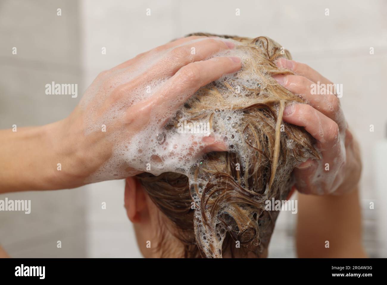 Woman washing hair with shampoo indoors, closeup Stock Photo