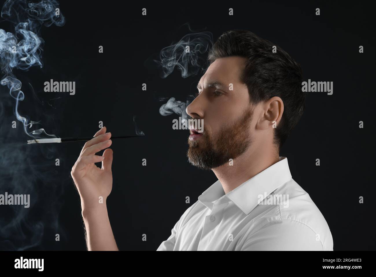 Man using long cigarette holder for smoking on black background Stock