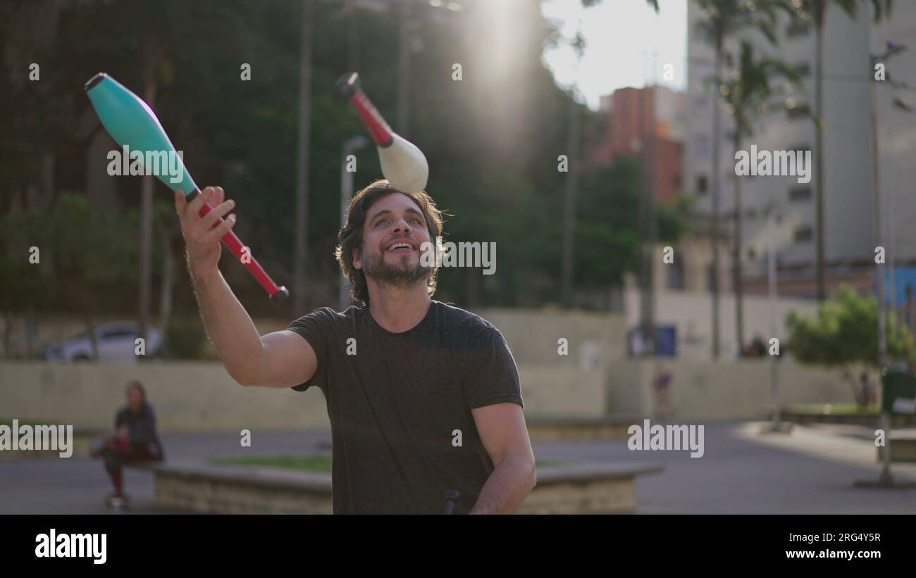Male Juggler performer demonstrating his skills outside in urban city park. Person artist