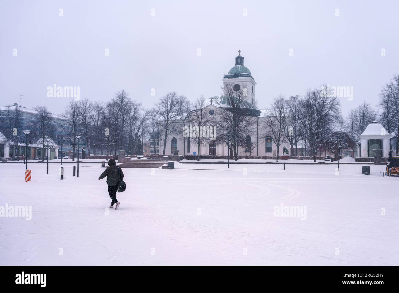 One person walking in Market Square in front of Hameenlinna church in winter. Finland, February 23, 2023. Stock Photo