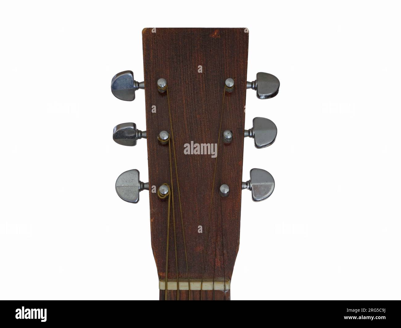 The wood headstock and tuning pegs of a homemade acoustic guitar are shown up close, set against a white background. Stock Photo