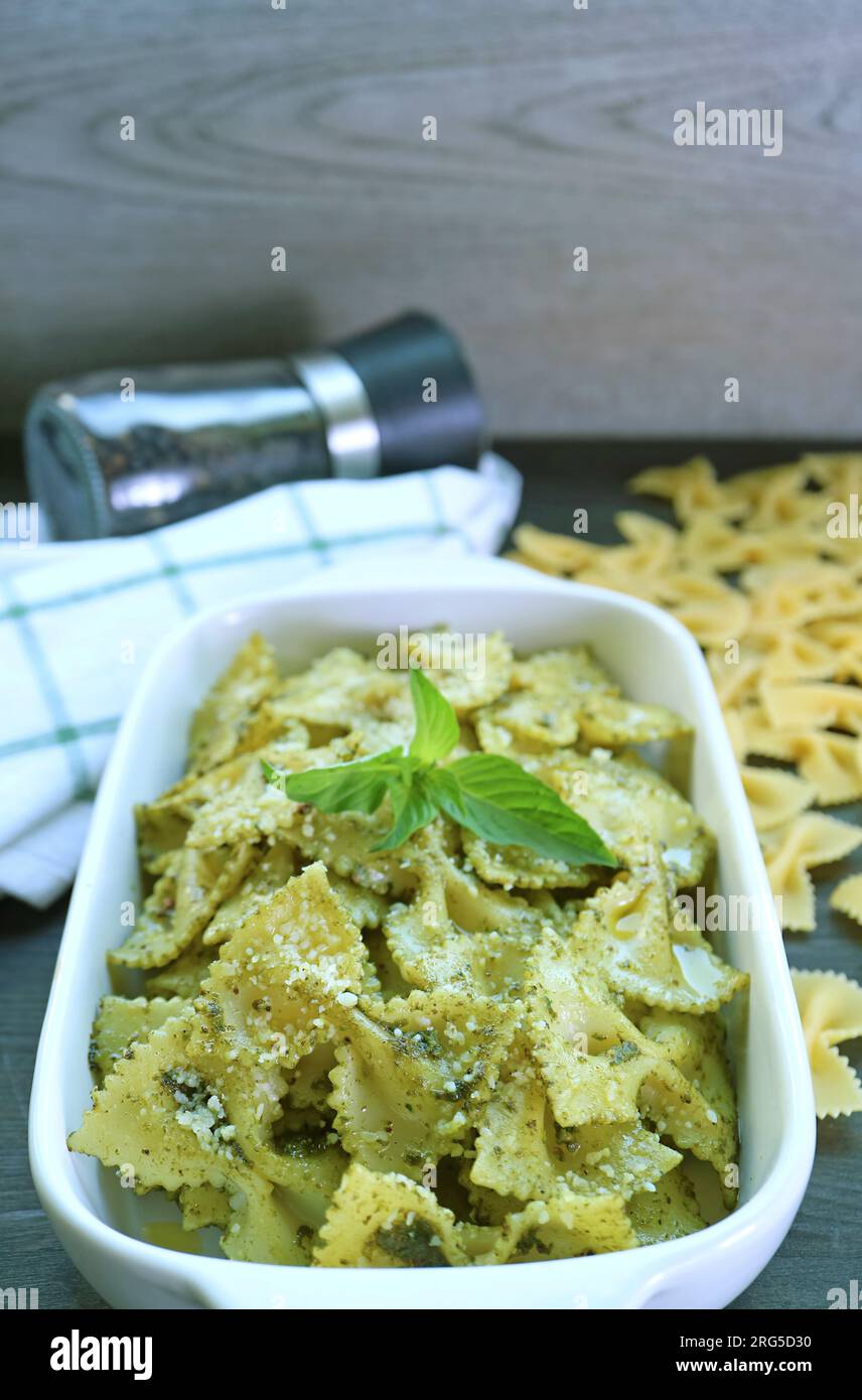Bowl of Delectable Homemade Farfalle Pasta with Pesto Sauce on Kitchen Table Stock Photo
