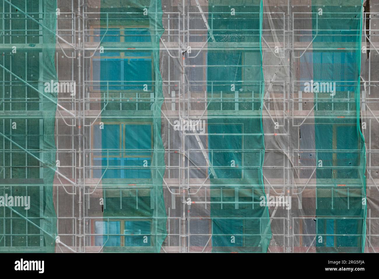 Colourful sheets of protective textile covers attached to the scaffolding on the exterior of a building under construction and renovation Stock Photo