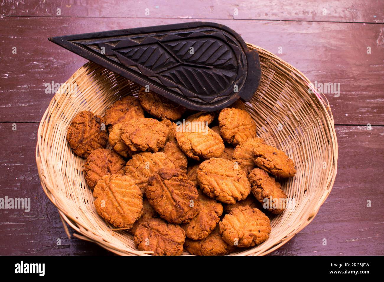 Thekua , an Indian sweet dish or a snacks in bamboo or wooden basket or tokri with mold in wooden table. popular in bihar jharkhand. Prashad in chhath Stock Photo
