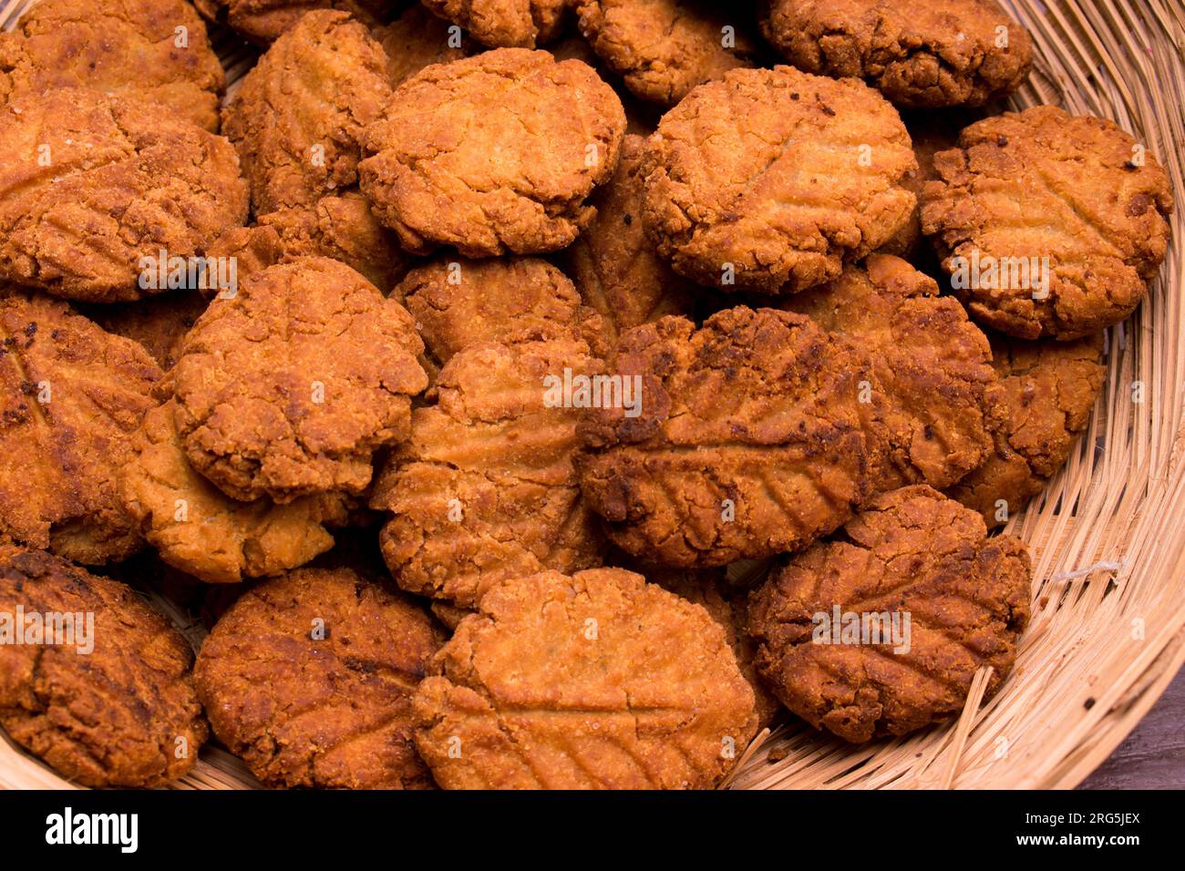 Thekua , an Indian sweet dish or a snacks in bamboo or wooden basket or tokri with mold in wooden table. popular in bihar jharkhand. Prashad in chhath Stock Photo