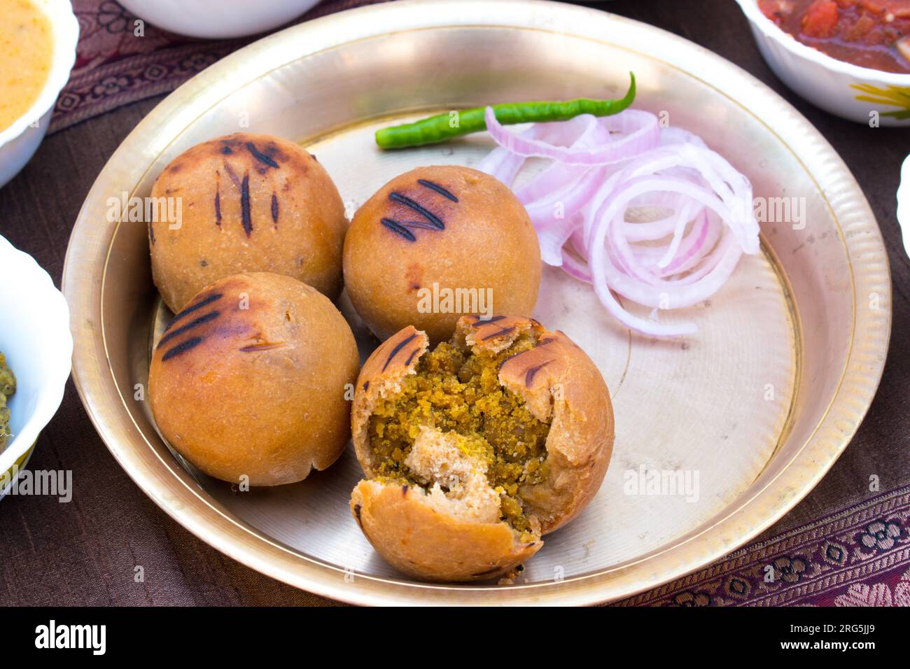 Litti with onion, chilli and chokha in brass plate. It is popular in Bihar, Uttar Pradesh and Jharkhand. Stock Photo