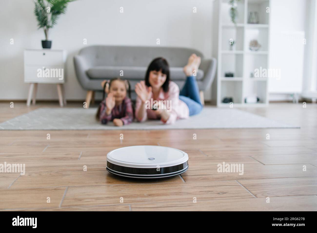 Smart robot vacuum saving mom and kid from tedious home work Stock Photo