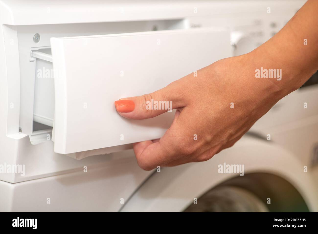 A woman opens the tray for pouring laundry detergent into the washing