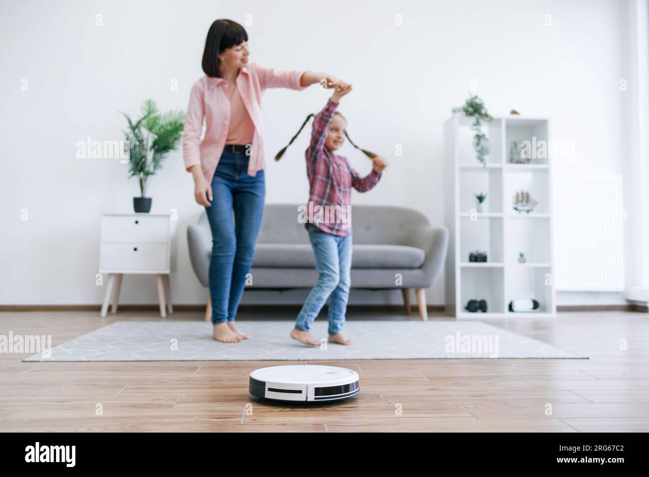 Mom twirling girl around while robot cleaner doing vacuuming Stock ...