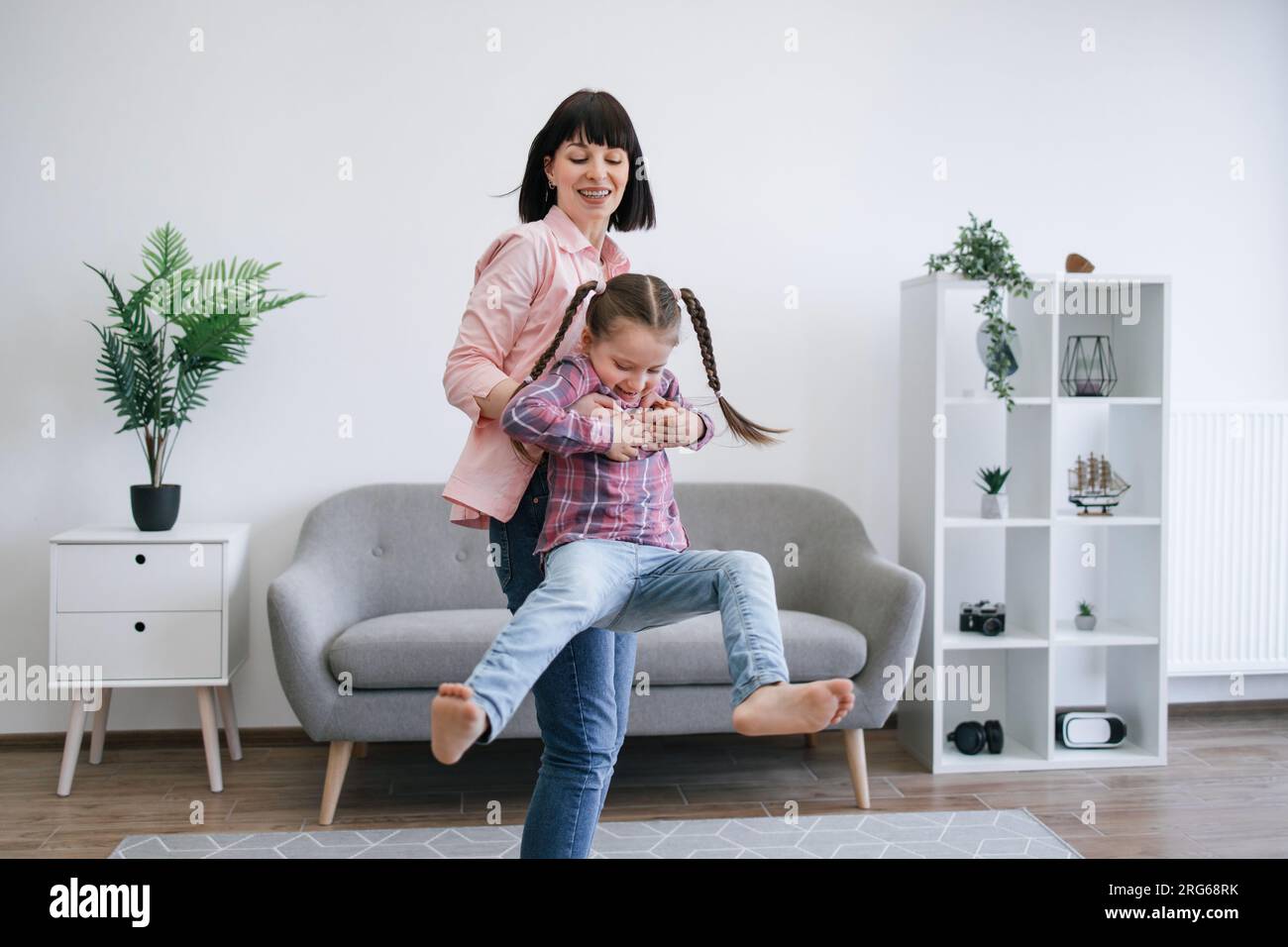 Mom twirling daughter around while staying indoors on day Stock Photo ...