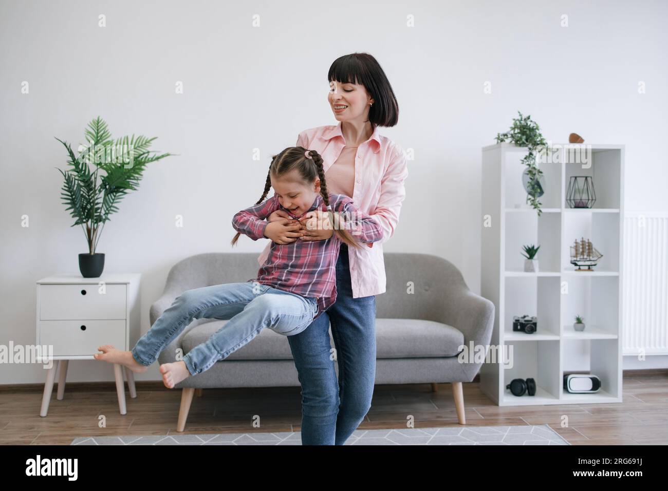 Mom twirling daughter around while staying indoors on day Stock Photo ...