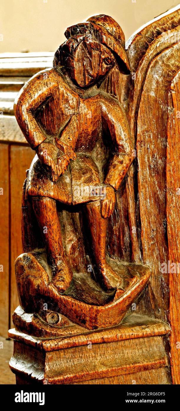 Medieval bench end, Anger, Seven Deadly Sins, man with knife in Jaws of Hell, Thornham church, Norfolk, England, UK Stock Photo