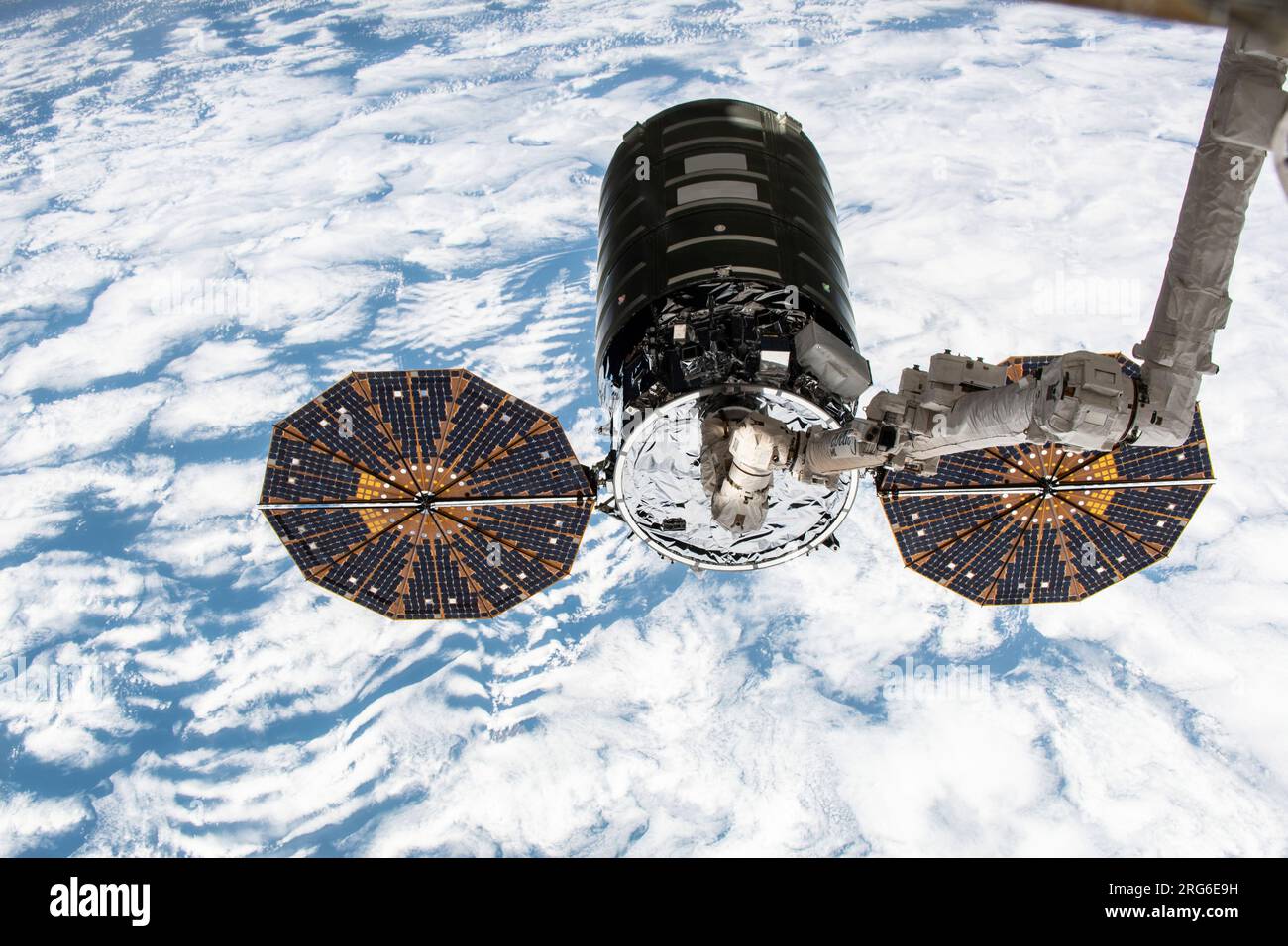 The Cygnus cargo spacecraft in the grips of the Canadarm2 robotic arm above Earth. Stock Photo