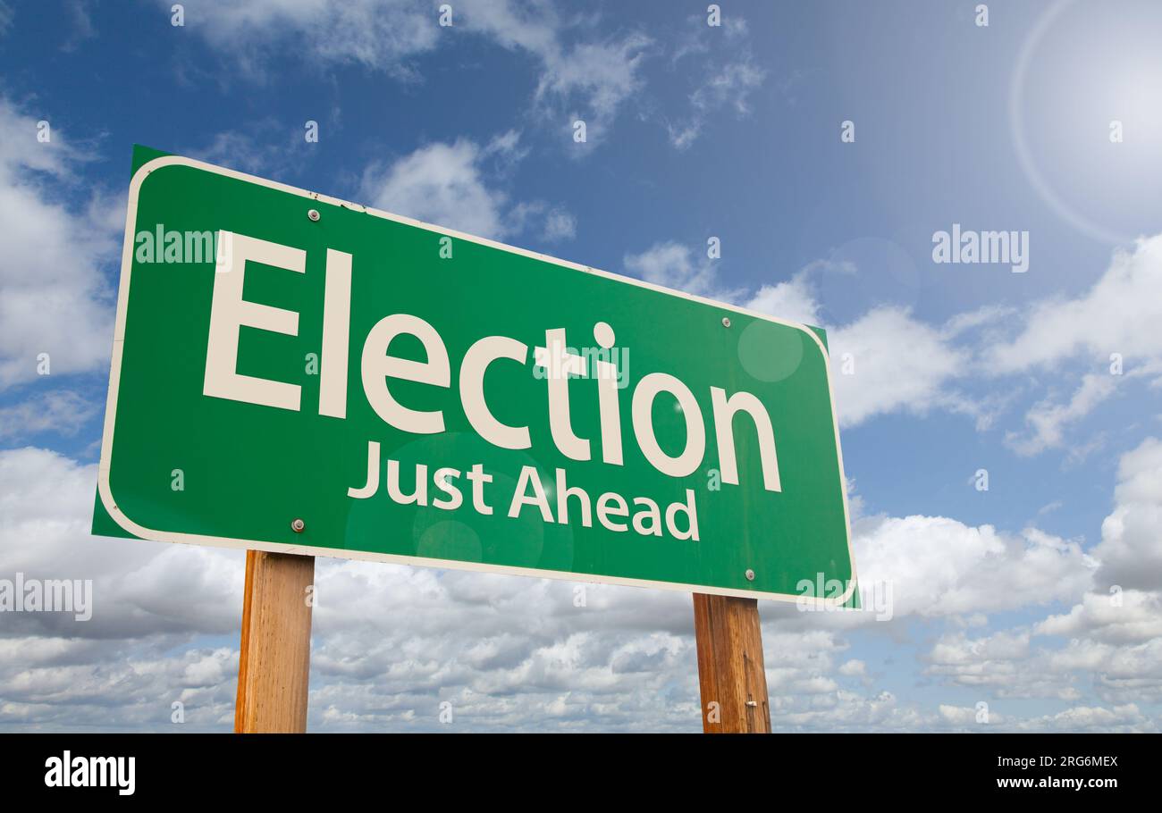 Election Just Ahead Green Road Sign Over Clouds and Blue Sky. Stock Photo