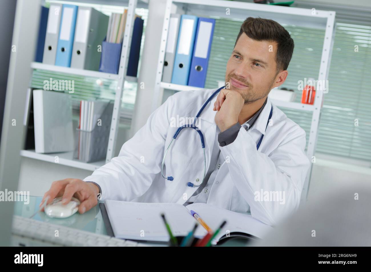 handsome male doctor smiling while using computer Stock Photo