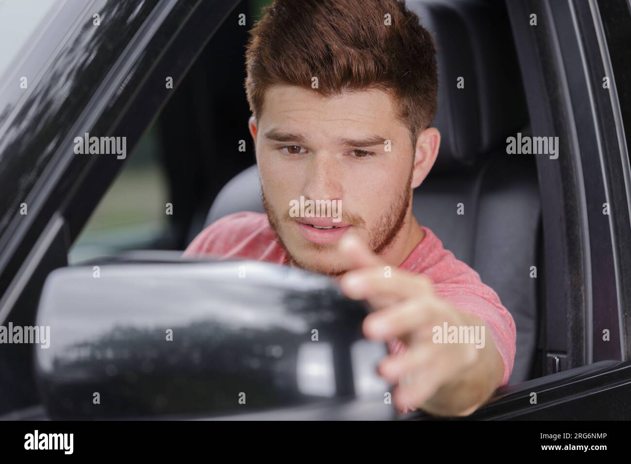 smiling guy fixing the rear view mirror of car Stock Photo Alamy