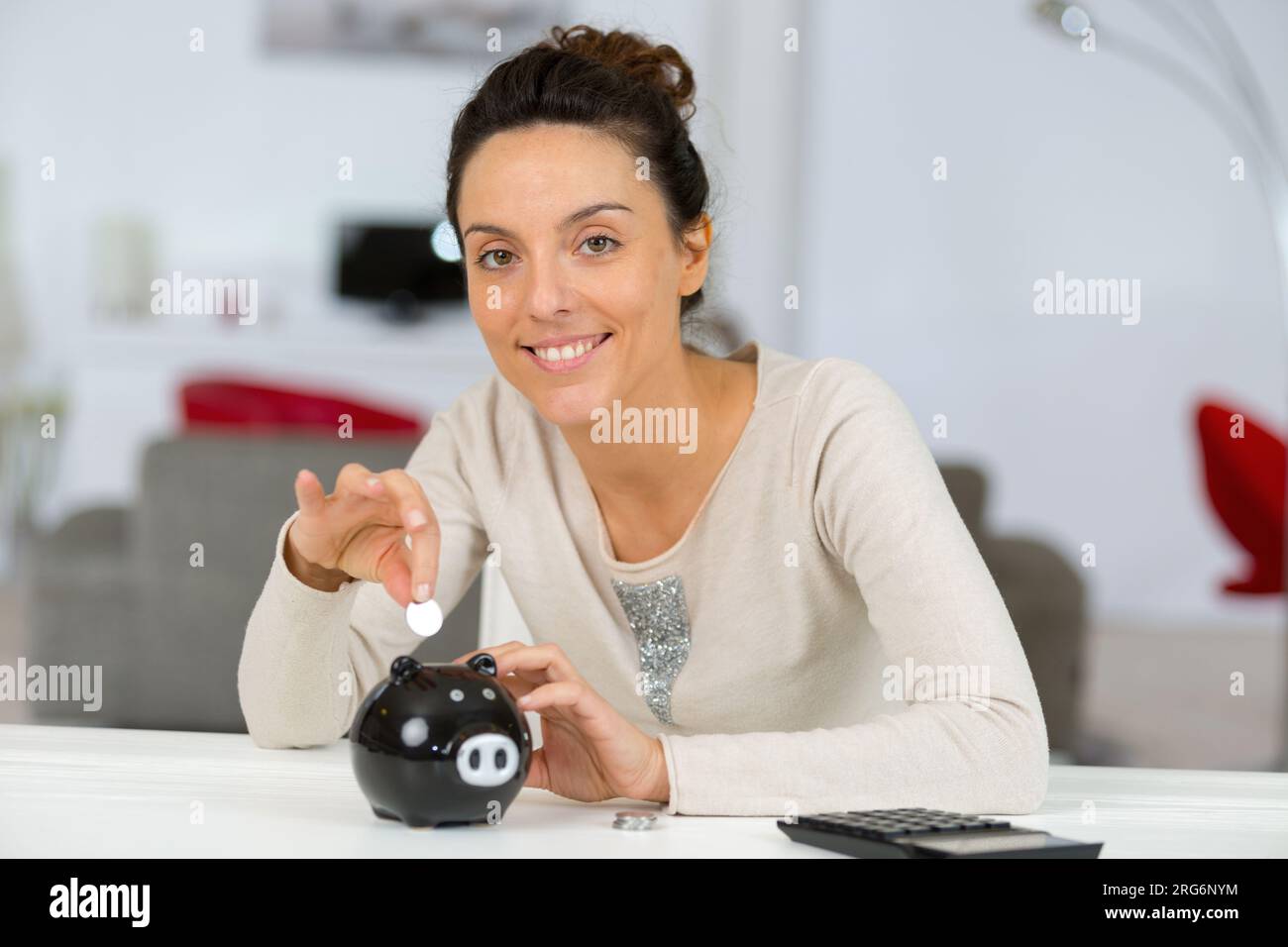 girl putting a coin in the piggy bank Stock Photo - Alamy