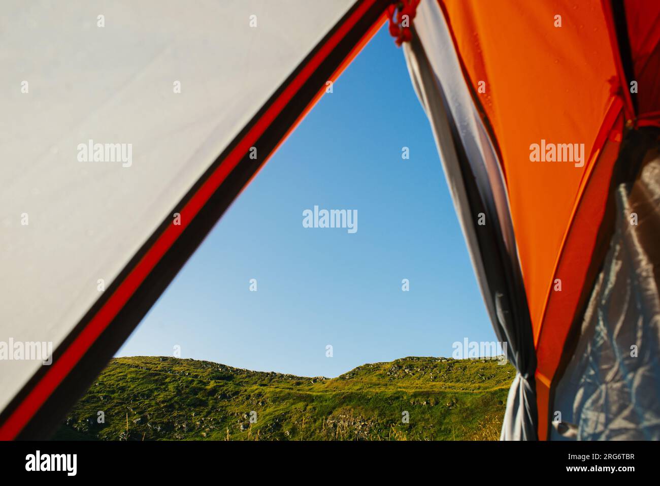 Scenic POV View from tent to mountains, Picturesque View From Orange Tent to the Mountains Carpathian, Outdoors scenes Summer Hiking Adventure Stock Photo