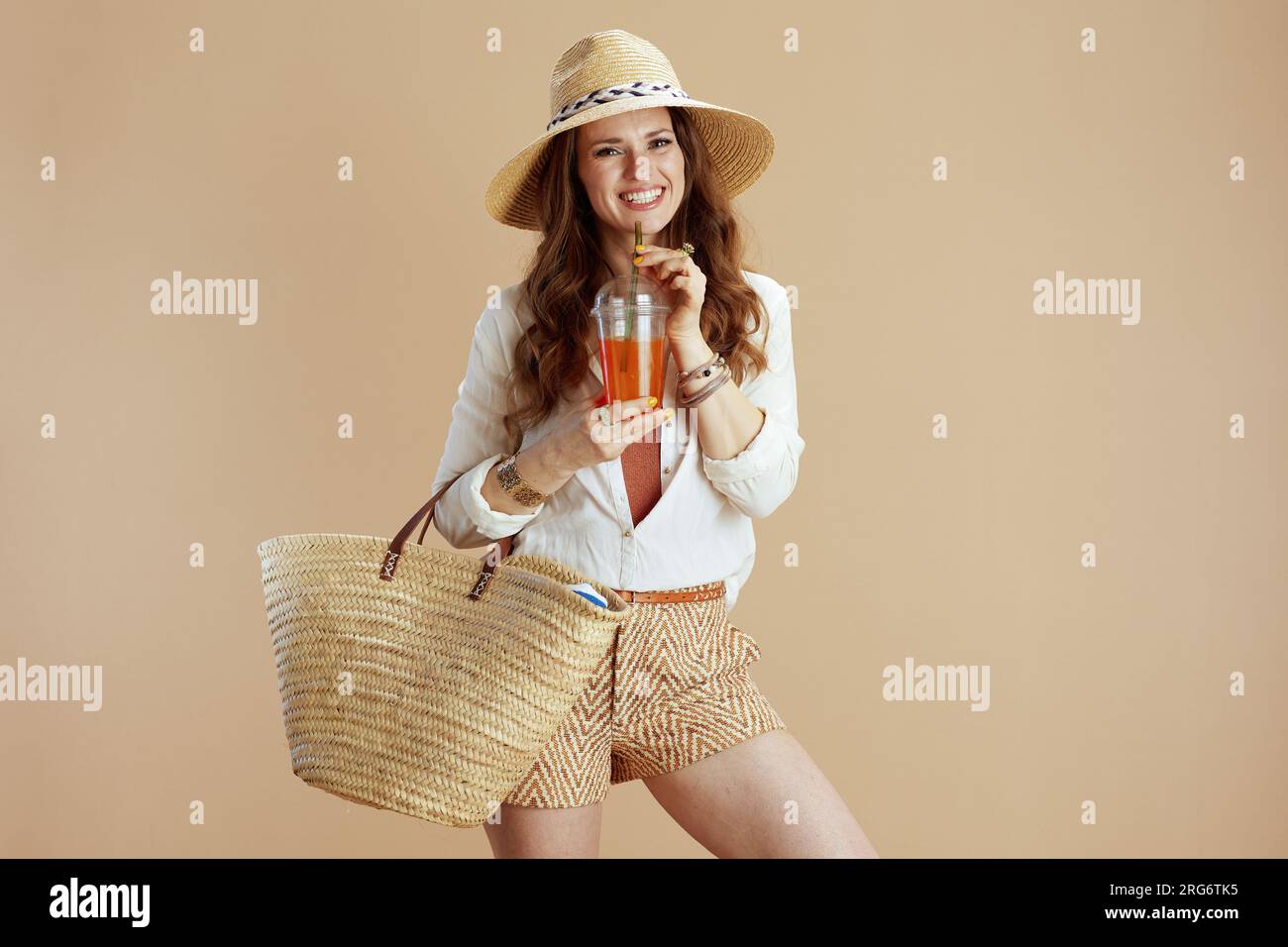 https://c8.alamy.com/comp/2RG6TK5/beach-vacation-happy-elegant-woman-in-white-blouse-and-shorts-isolated-on-beige-background-with-straw-bag-carrot-juice-and-summer-hat-2RG6TK5.jpg