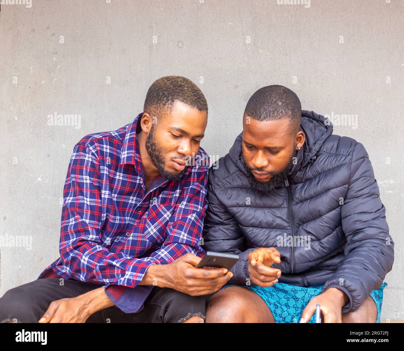 Two teens using mobile phone while relaxing in a park, Stock Photo