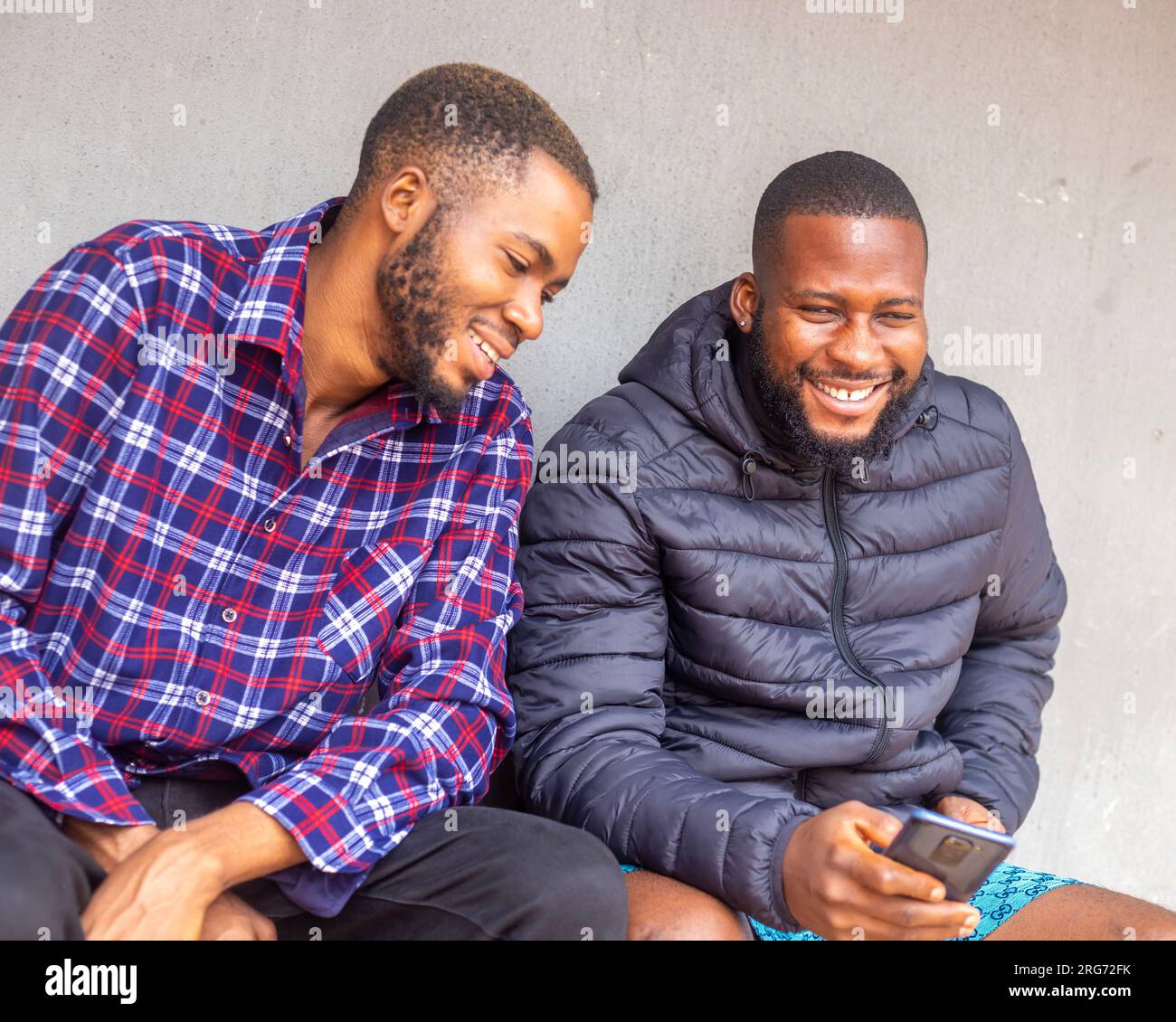 Two teens using mobile phone while relaxing in a park, Stock Photo