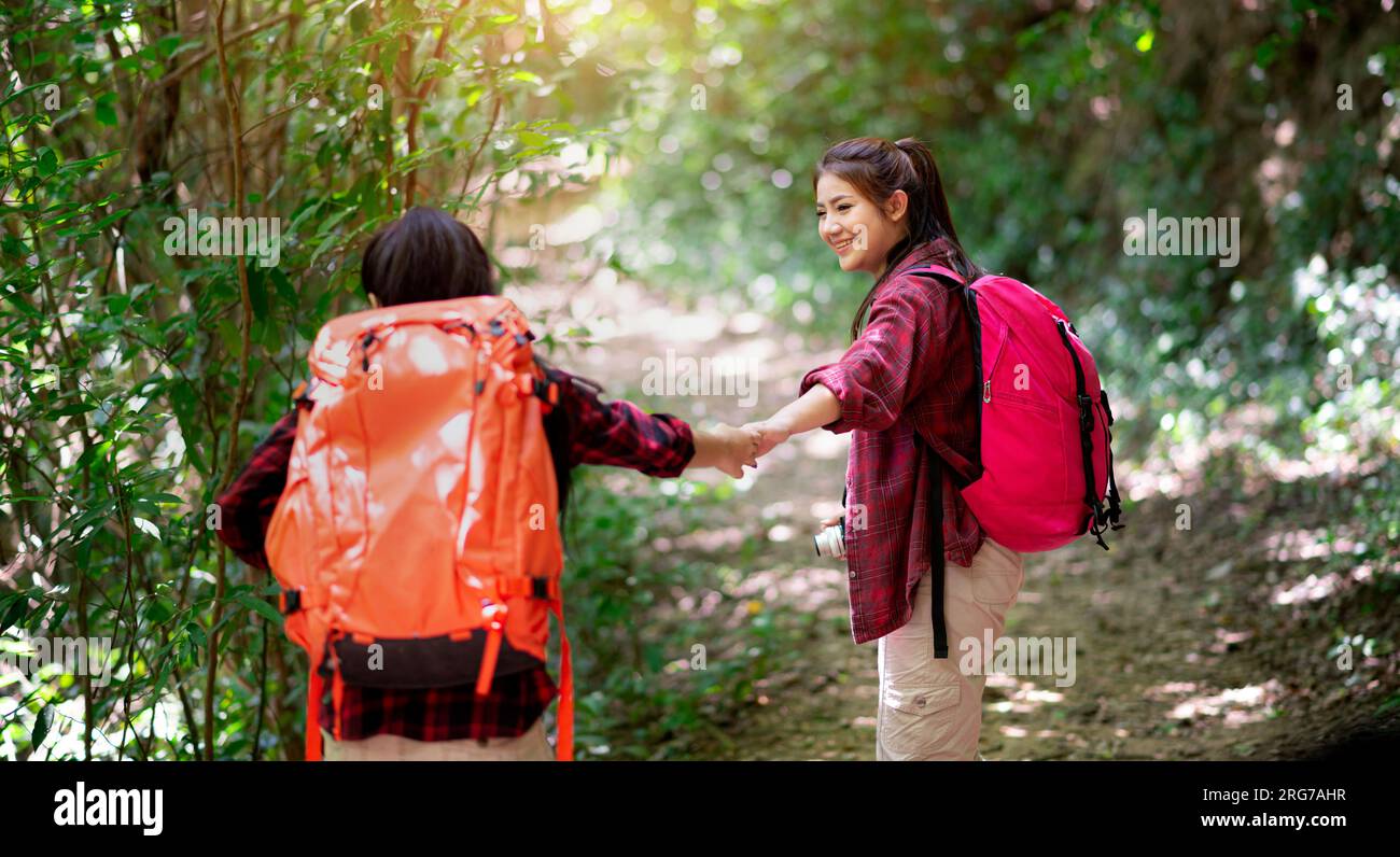 Two hikers with backpacks walking in the forest enjoying the valley