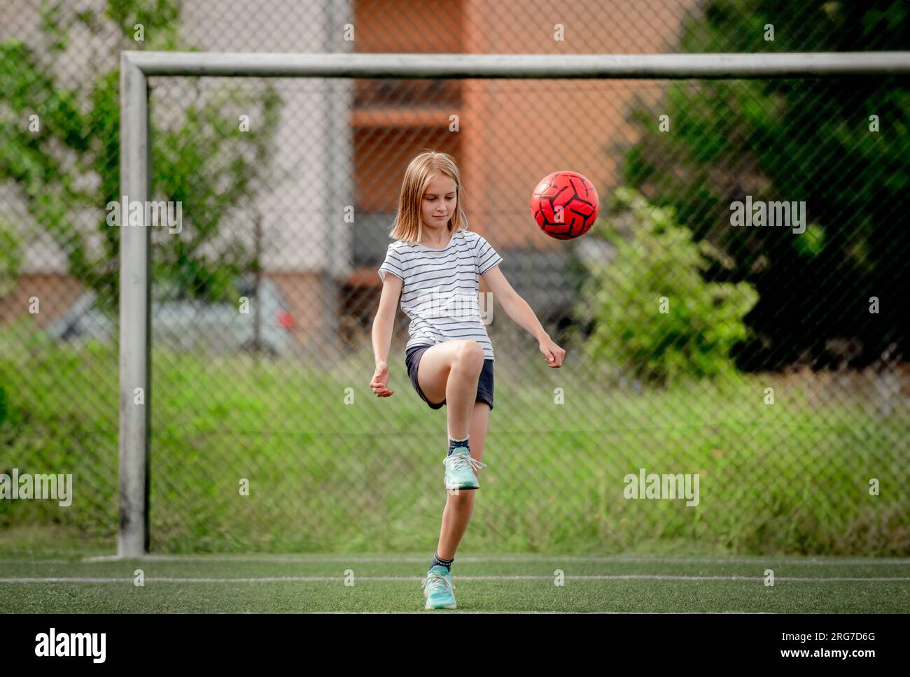 Pretty child girl kicking football ball at socket field. Cute female ...