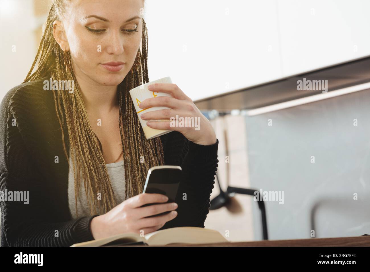 Reading in her sunny kitchen, a lovely lady knows exterior beauty fades but inner intellect and peace remain, guiding her through life's struggles Stock Photo