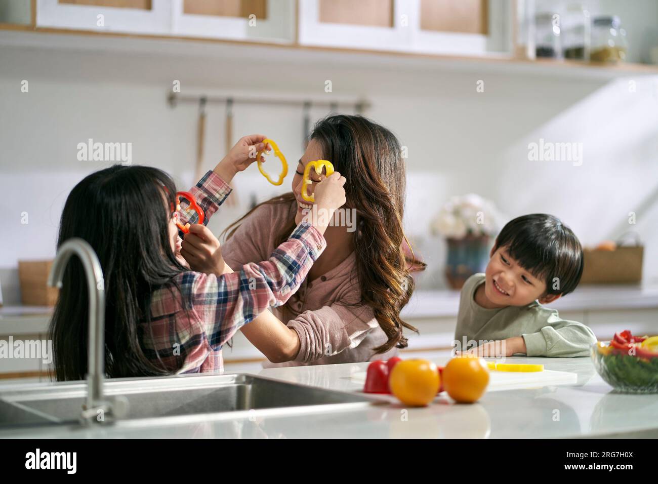 young asian mother having fun with two children in family kitchen at home Stock Photo