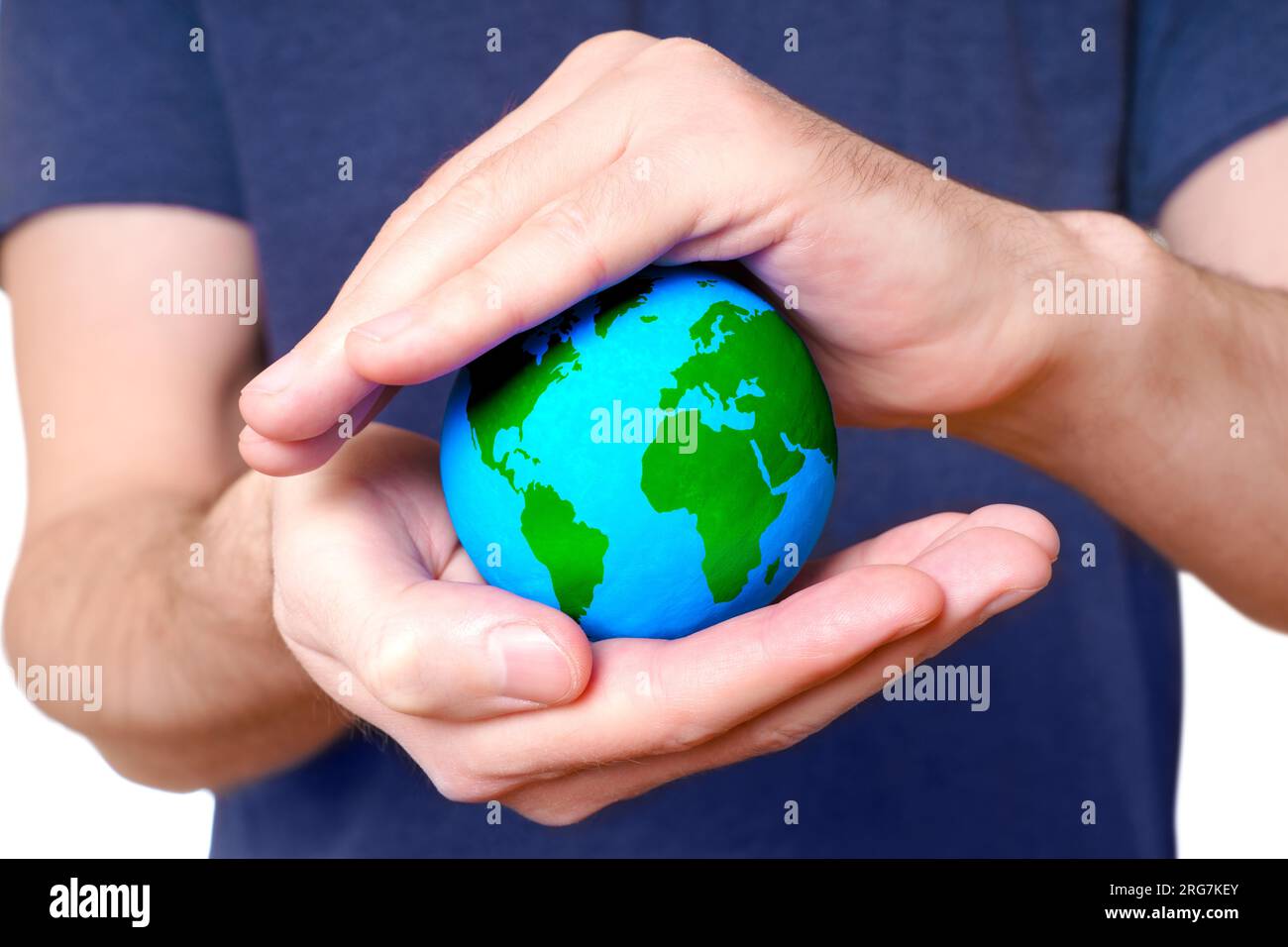 Small green and blue globe is cradled between cupped hands, that serve as a shelter, emphasizing the need to safeguard our environment and promote a s Stock Photo