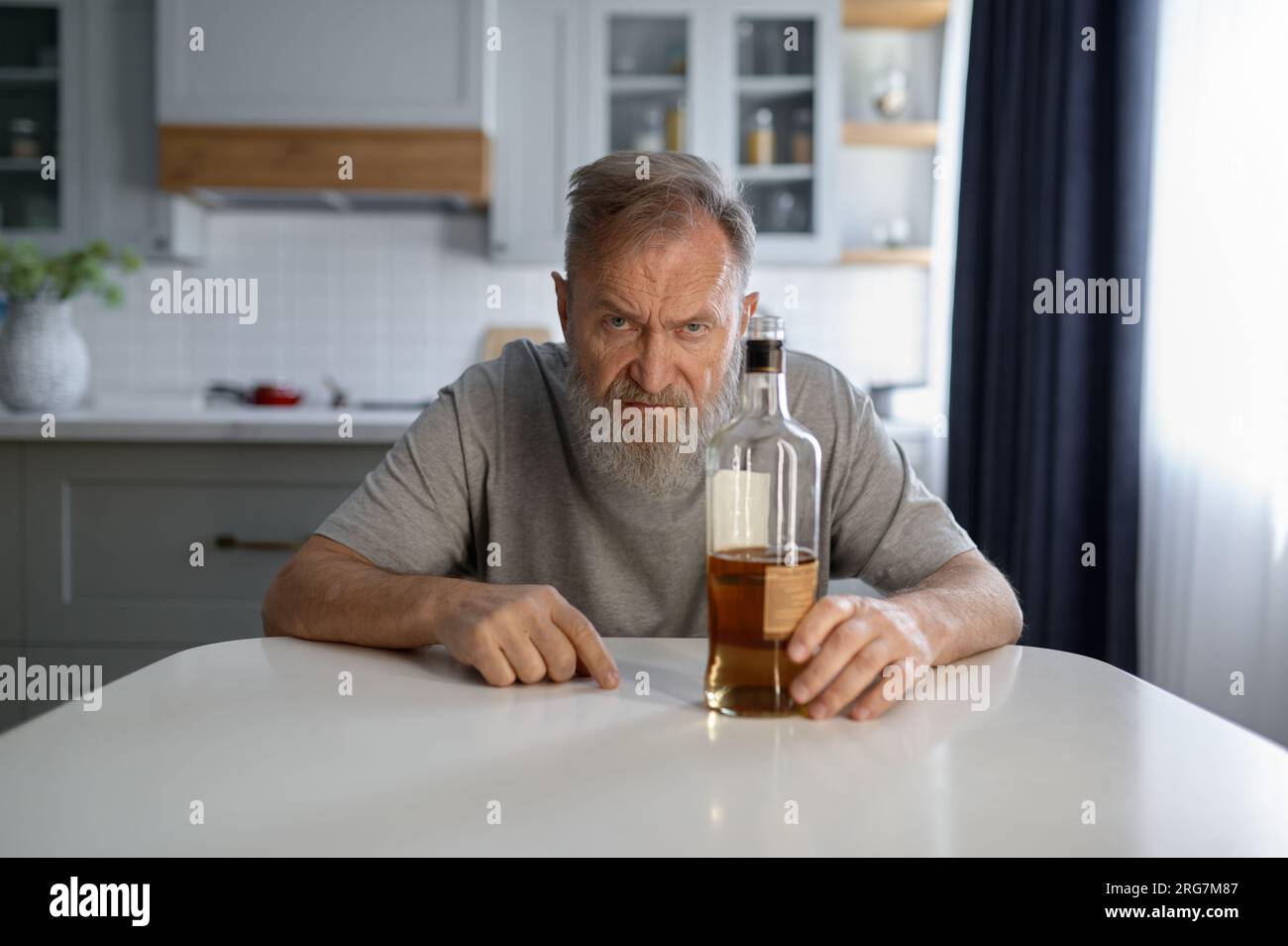 Portrait of lonely drunk man feeling depressed on home kitchen Stock Photo