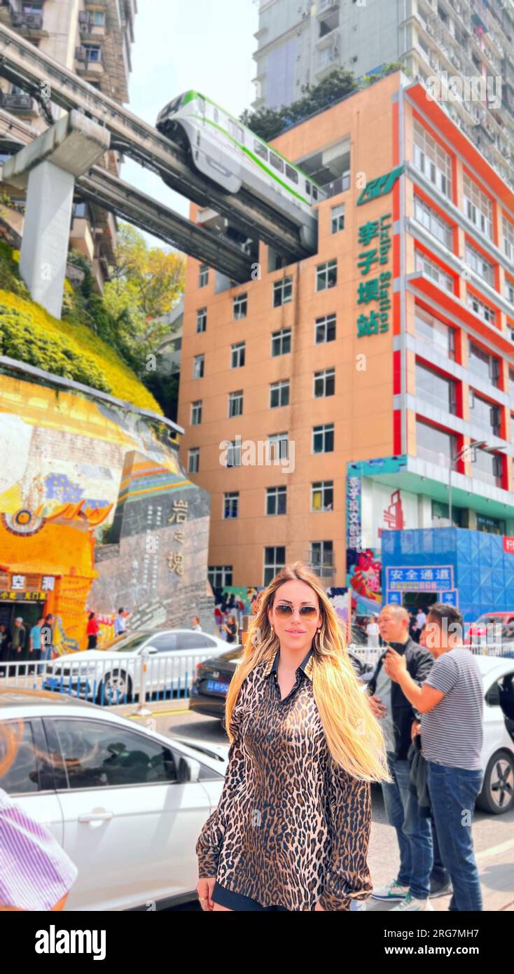 Chongqing. 8th Aug, 2023. Yasmin Von Roon poses for a photo as a train runs through a 19-story residential building at Liziba Station of Chongqing Rail Transit Line 2, southwest China's Chongqing, on April 27, 2023. Italian girl Yasmin Von Roon is a successful online influencer with 110,000 fans on TikTok, but she still recalls the strong emotional impact of learning about Marco Polo's travels.TO GO WITH 'Across China: Italian vlogger shares enduring passion for China' Credit: Xinhua/Alamy Live News Stock Photo