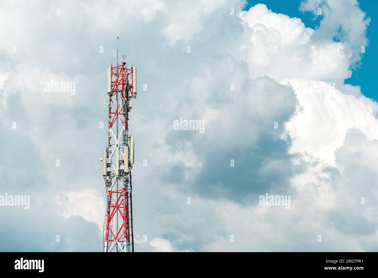 Mobile telephony base station on communication tower against cloudy summer sky Stock Photo