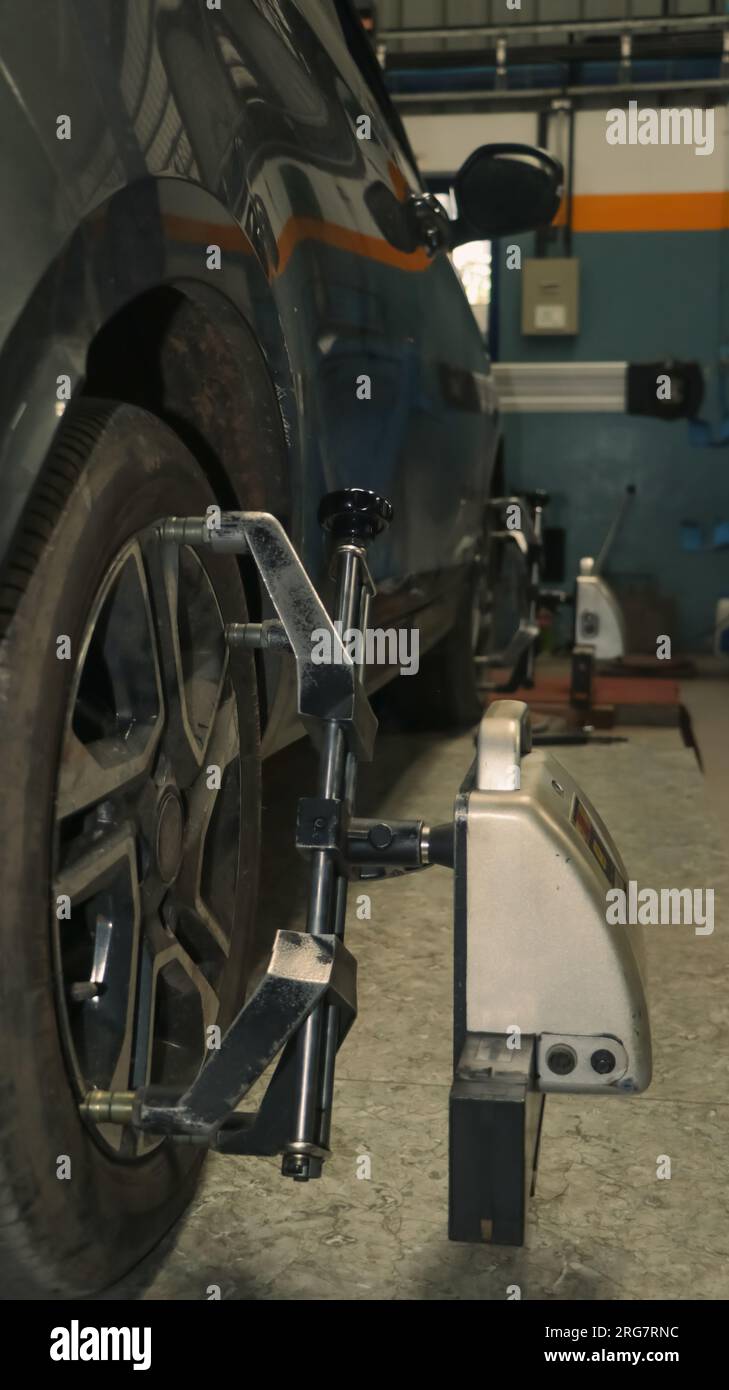 a car tire under maintenance and correction of steering camber, caster and toe angles using a 3D wheel alignment sensor tool in an auto repair shop an Stock Photo