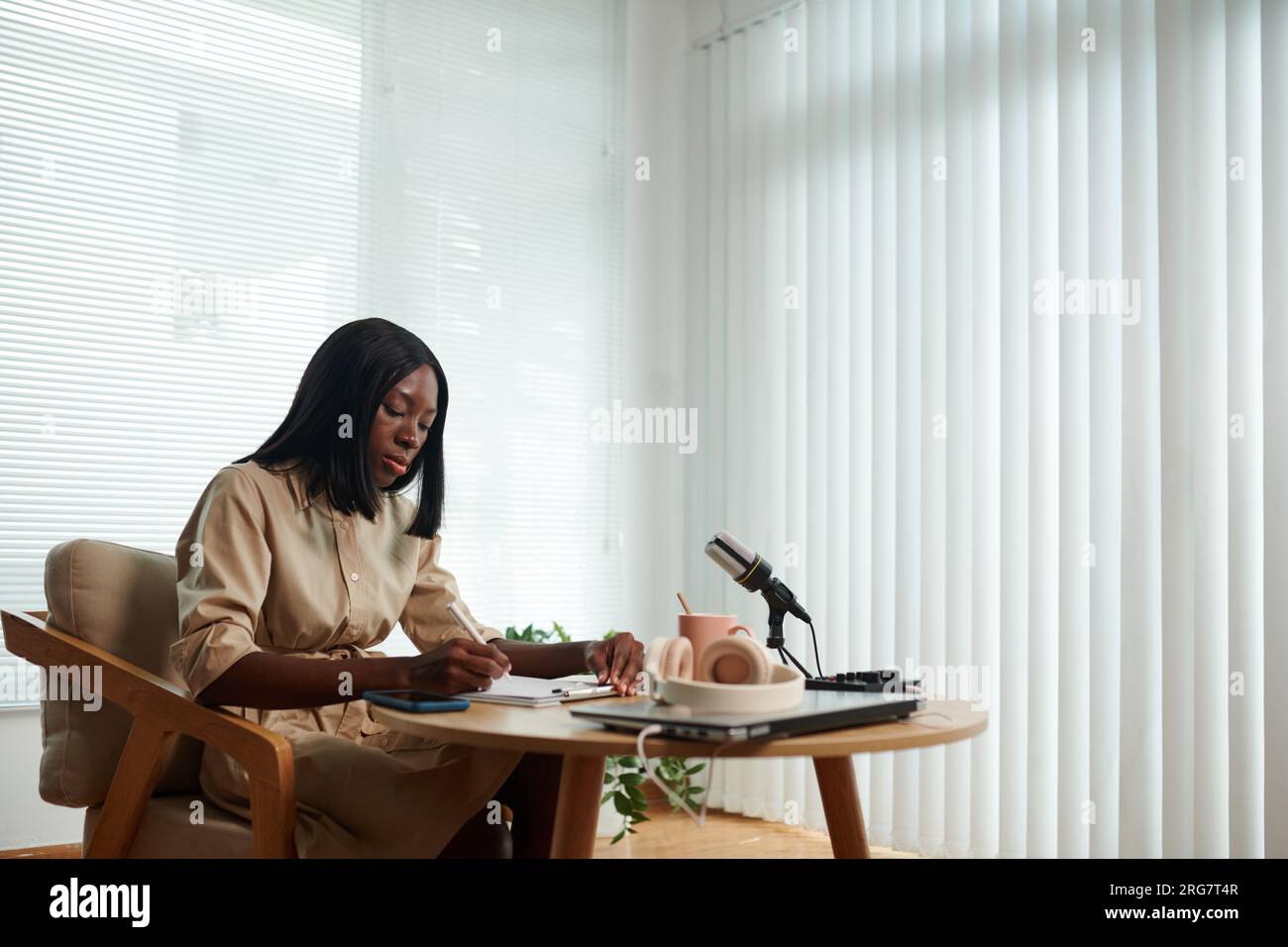 Serious Black young woman working on script for her podcast Stock Photo