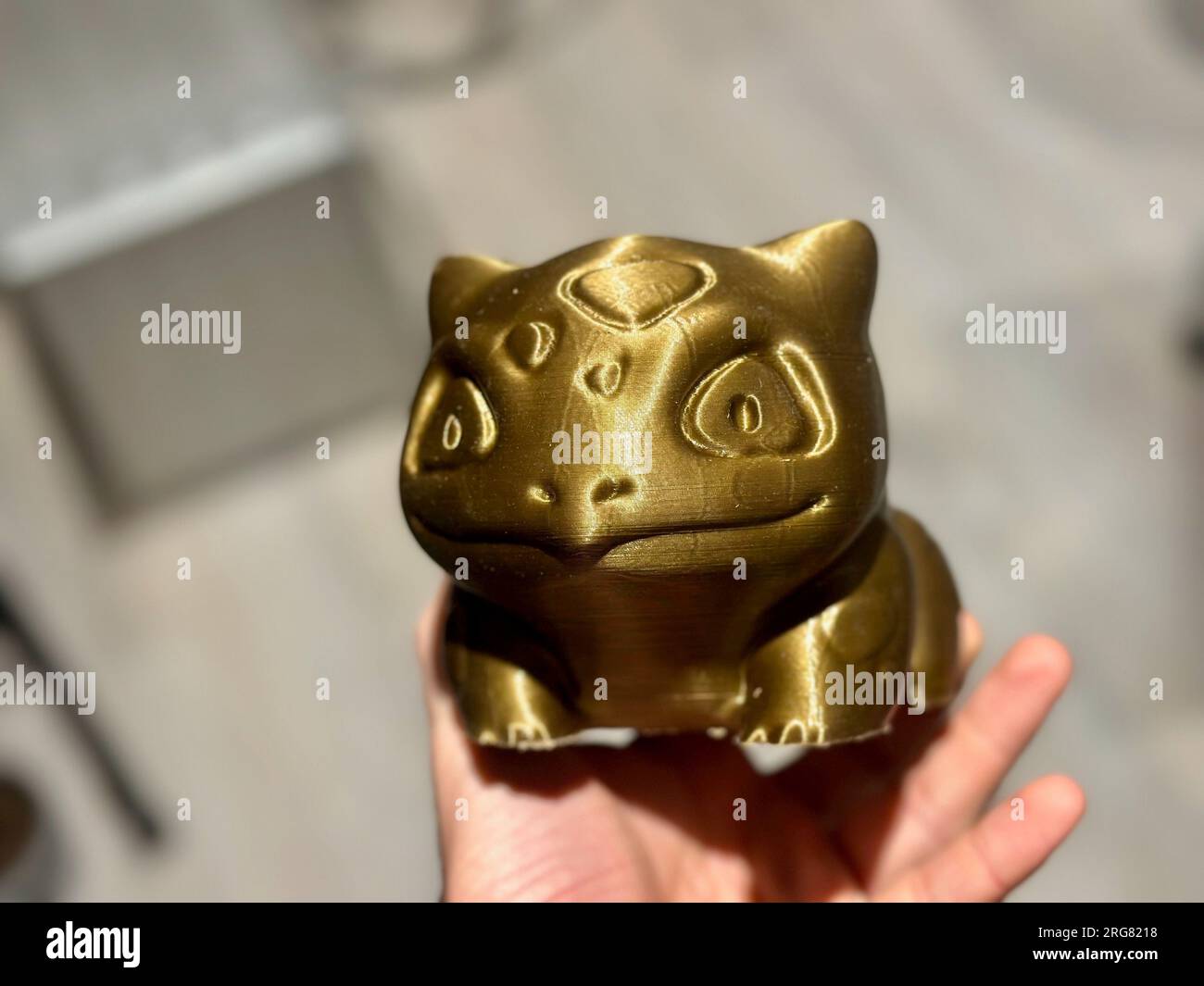 The Technological Alchemy: A 3D Printed Golden Bulbasaur Figurine - Fusion of Fantasy and Reality, A Cultural Crossover Between Cartoon and Material W Stock Photo