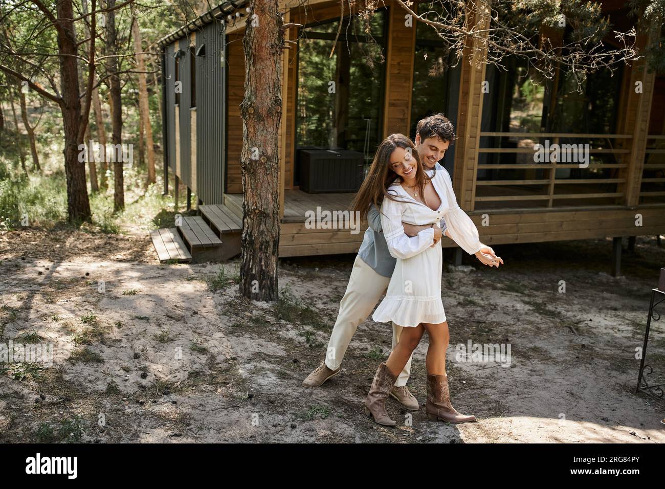 happy man hugging woman and smiling near vacation house, forest, summer ...