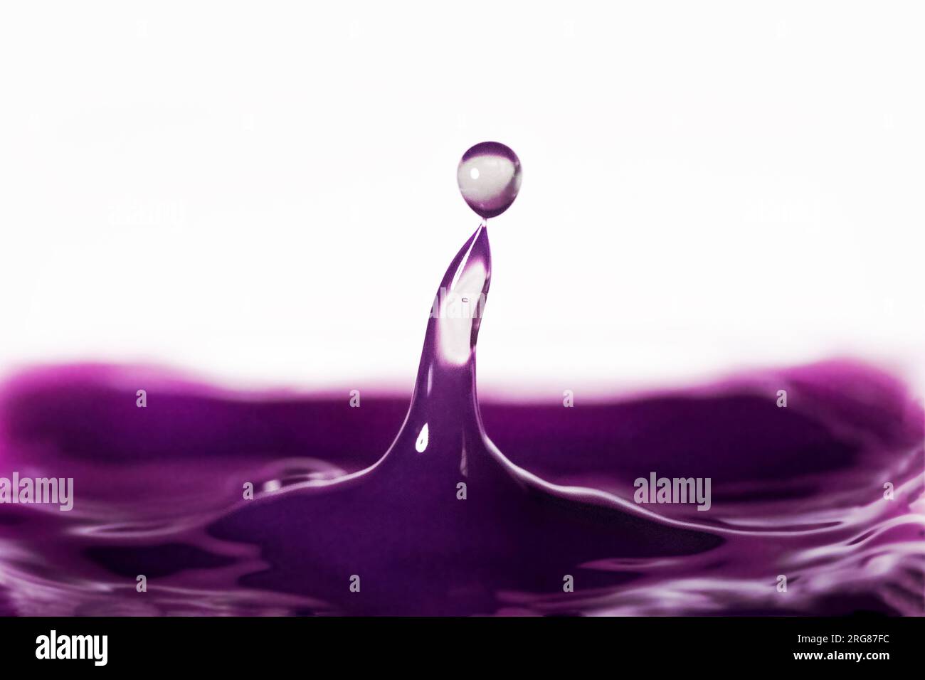 Purple water drop creating a sphere of water on top of a column of