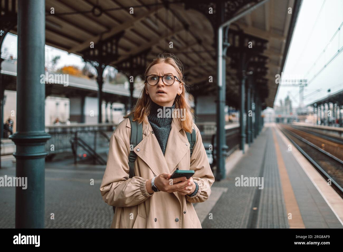 Angry lost woman waiting on the station platform and using smart phone at the airport link station, Gdansk, Poland. Stock Photo
