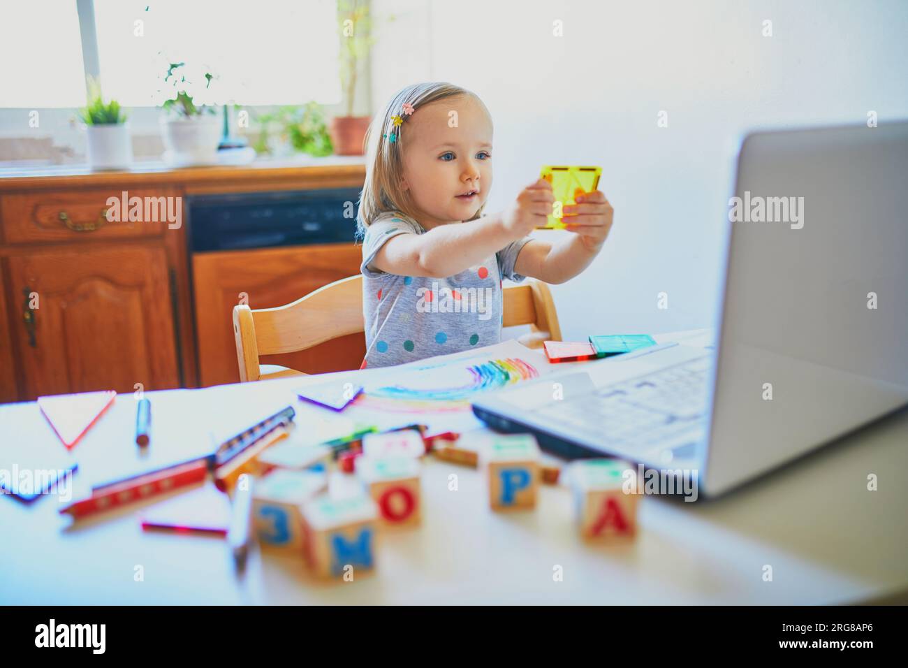 Toddler girl learning shapes in front of laptop. Kid using computer to ...