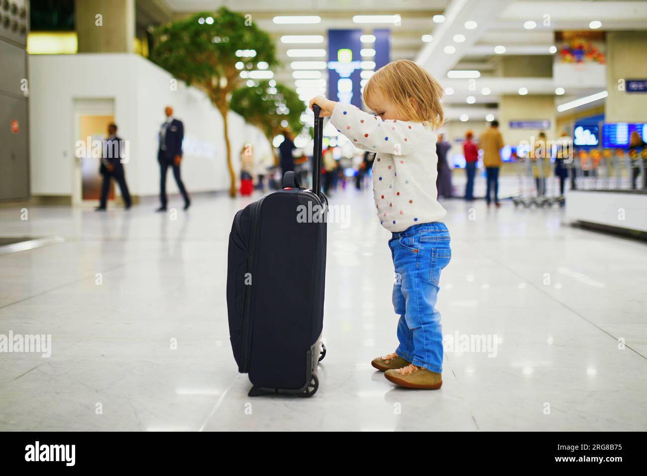 Adorable little girl in the airport. Toddler with carryon luggage. Travelling with small kids