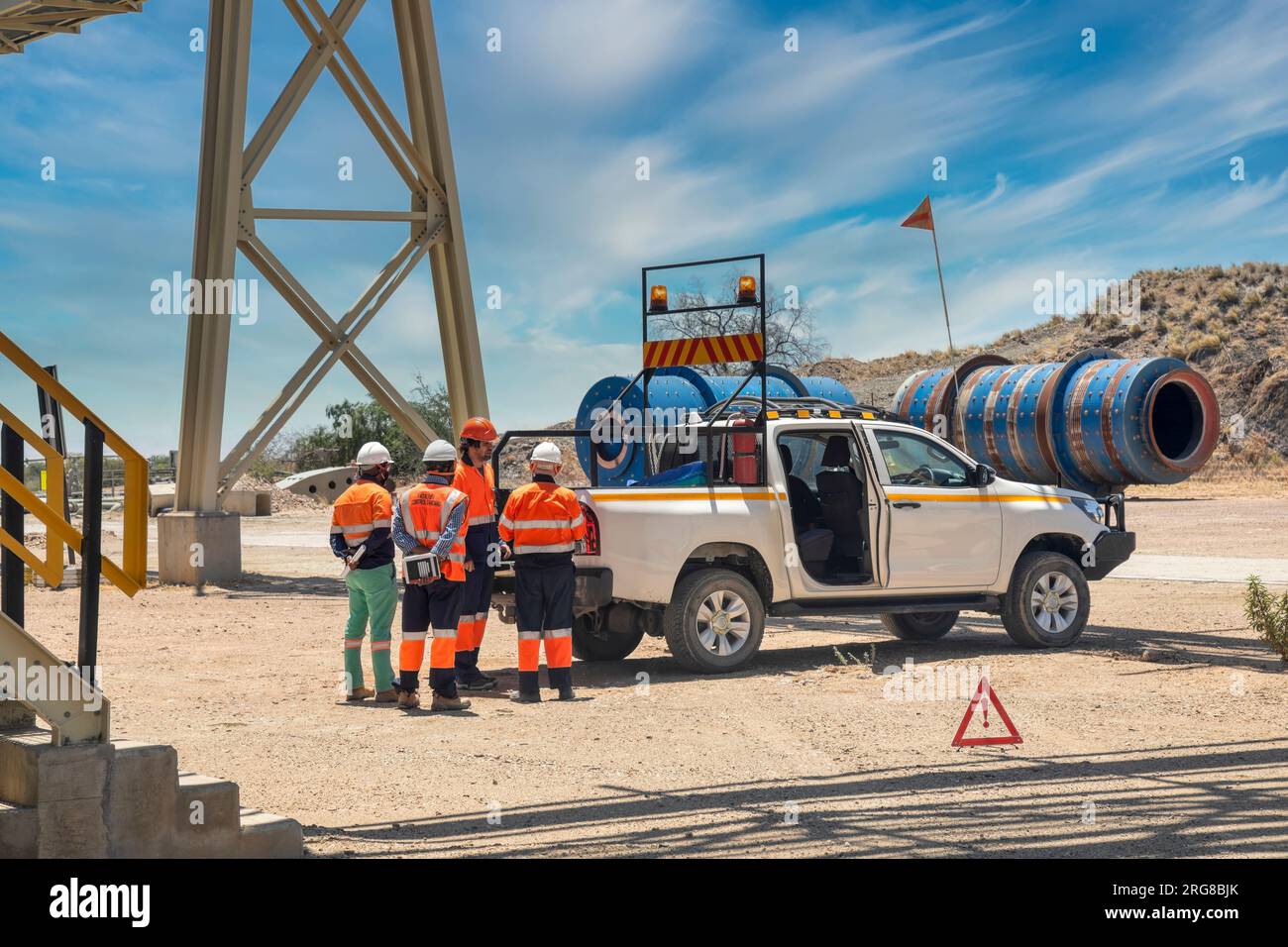 diamond mine managerial team discussing work plans behind a 4x4 vehicle on a dirt road under a bridge Stock Photo