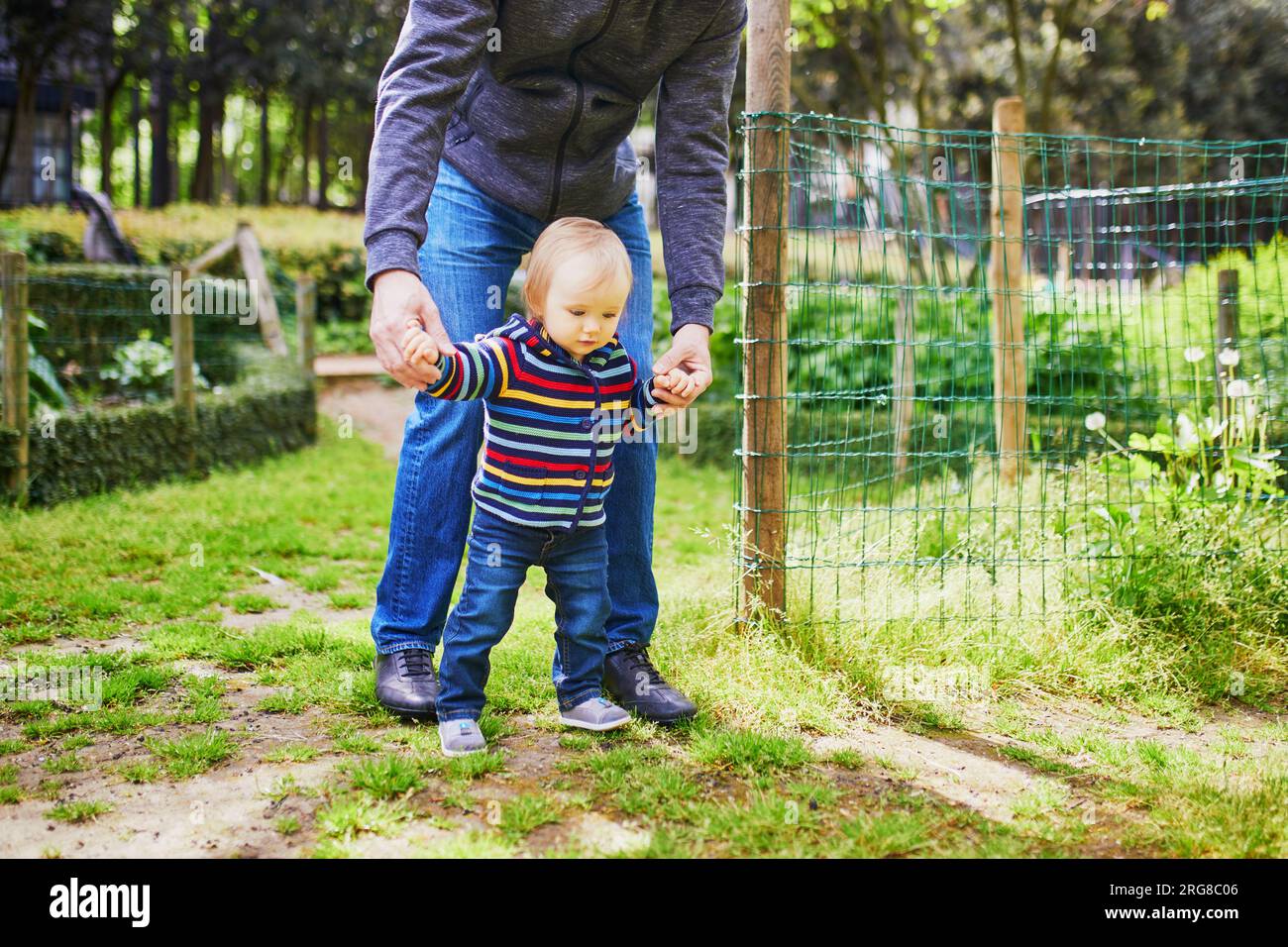 Man with 1 year old baby girl in park. Father helping his daughter make